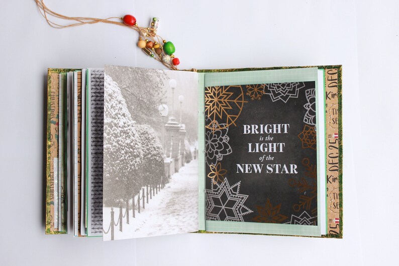 May include: An open book with a black and white photo of a snowy path on the left page and a black background with gold and white snowflakes and the text "BRIGHT is the LIGHT of the NEW STAR" on the right page.