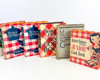 Puede incluir: Una colección de libros de cocina vintage. Los libros presentan patrones de cuadros rojos y blancos, con títulos como "Better Homes" y "Junior Cook Book". Las portadas muestran ilustraciones y texto, evocando una estética retro. Dispuestos sobre una superficie blanca.