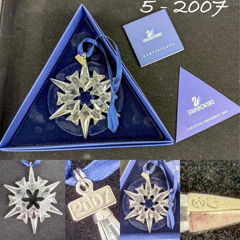 May include: A clear faceted crystal snowflake ornament with a blue ribbon and a metal tag engraved with 2007. The set includes a triangular blue presentation box, a certificate of authenticity, and a triangular card labeled Swarovski Christmas Ornament 2007.