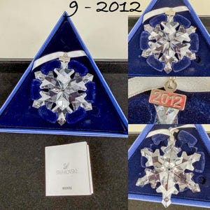 May include: A clear faceted crystal snowflake ornament with a white ribbon and a silver-toned metal tag engraved with the year 2012. The ornament is presented in a triangular blue box with a dark blue velvet insert and includes a Swarovski warning booklet.