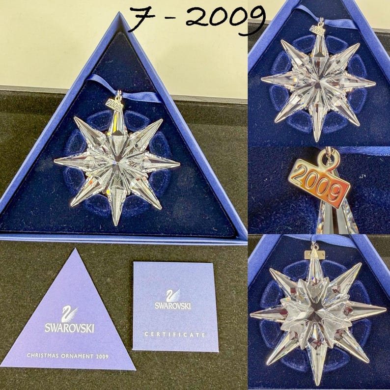 May include: A clear, multi-pointed star-shaped crystal ornament with a silver-toned metal tag engraved with the year 2009. The ornament is presented in a triangular blue box with a blue ribbon and includes a Swarovski certificate of authenticity.