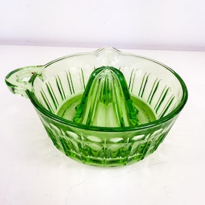 Peut inclure: Presse-agrumes vintage en verre vert. Le presse-agrumes comporte un presse-agrumes au centre et un bol avec une poignée. Le verre présente un design nervuré et géométrique. Il est conçu pour presser les agrumes.