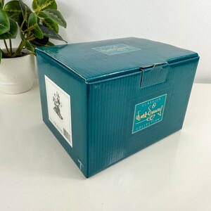 Op de afbeelding: Een turquoise doos met de woorden "Classics" en "Walt Disney Collection" in gouden letters. De doos heeft een wit etiket met een zwart-wit afbeelding en een barcode. Een kleine plant in een pot staat op de achtergrond.
