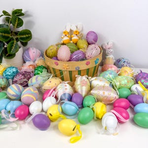 May include: A collection of colorful Easter eggs in various designs and sizes, including striped, glittered, and solid colors. Some eggs are in a decorative basket with bunny figurines, perfect for Easter decorations.