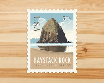 Puede incluir: Un sello postal con Haystack Rock en Cannon Beach, Oregón. El sello muestra una formación rocosa marrón, una playa arenosa y un cielo azul claro con nubes. El sello dice "USA" y "50¢".