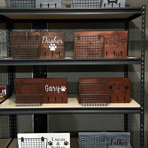 May include: A shelf unit with multiple wooden signs featuring dog names and paw prints. Each sign has a wire basket attached. The signs are in various colours, including grey, brown, and white.
