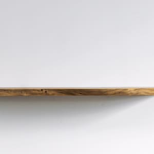 Pode incluir: Uma prateleira longa de madeira com acabamento natural. A prateleira est&aacute; montada em uma parede branca.
