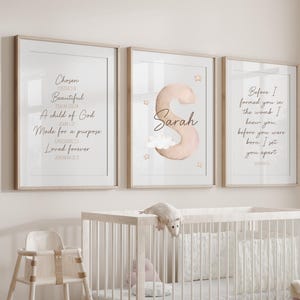 May include: A nursery scene featuring three framed prints with inspirational quotes and a personalized name. The prints are above a white crib, a high chair, and decorative baskets filled with stuffed animals. The prints have text that reads "Chosen", "Beautiful", and "Sarah".