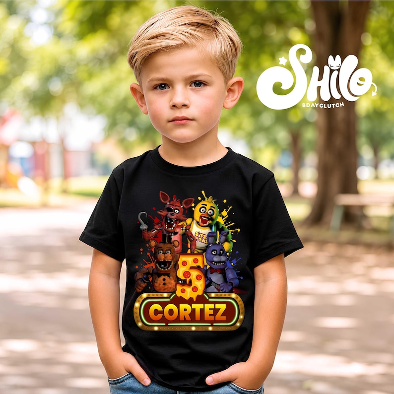May include: A black short-sleeved t-shirt featuring a graphic print of four animated characters, a large number 5 with a pizza-slice pattern, and a glowing neon-style sign with the name CORTEZ printed in bold yellow capital letters.