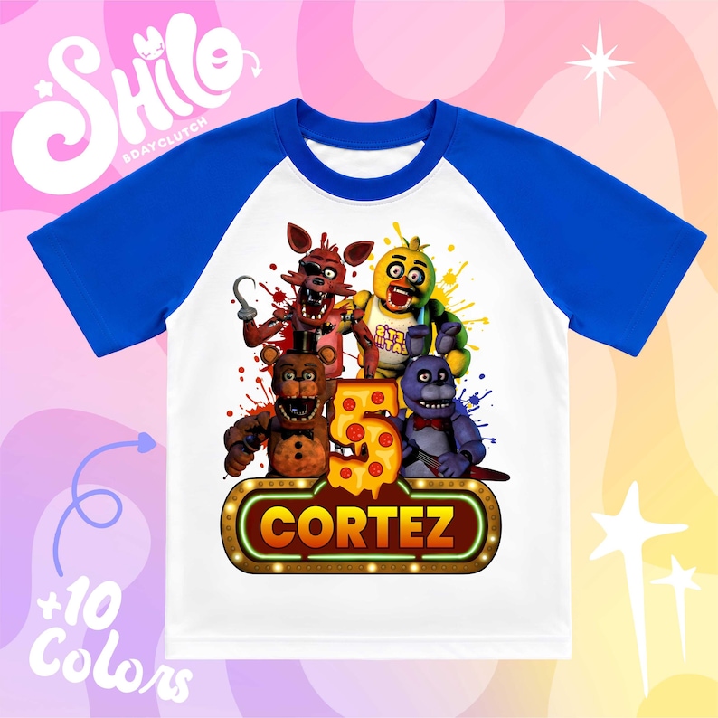 May include: A white and blue raglan t-shirt featuring a graphic of four animatronic characters from Five Nights at Freddy's, a large number 5 shaped like pizza, and a glowing marquee sign with the name CORTEZ printed in bold orange letters.