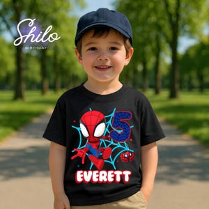 Pode incluir: Uma crian&ccedil;a usando uma camiseta preta de anivers&aacute;rio com tema do Homem-Aranha com o nome "Everett" impresso. A camisa apresenta um desenho animado do Homem-Aranha, o n&uacute;mero azul "5" e um design de teia de aranha. A crian&ccedil;a tamb&eacute;m est&aacute; usando um bon&eacute; de beisebol azul marinho.