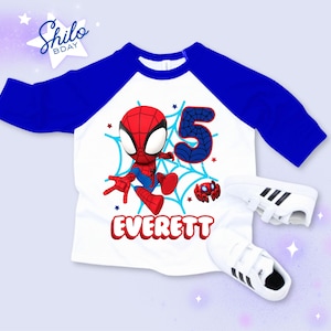 Pode incluir: Uma camisa branca e azul estilo raglan com um gr&aacute;fico do Homem-Aranha, o n&uacute;mero 5 e o nome "Everett" em vermelho. T&ecirc;nis brancos com listras pretas tamb&eacute;m est&atilde;o na imagem. A camisa &eacute; projetada para um anivers&aacute;rio.