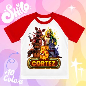 May include: A white t-shirt with red raglan sleeves featuring a graphic print of four animated characters, a large yellow number five with pepperoni details, and a rectangular sign with the name CORTEZ in bold yellow letters on a brown background.