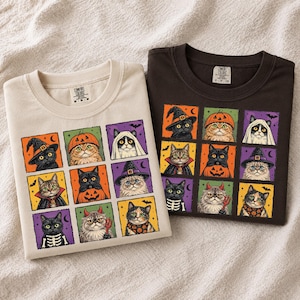 K&ouml;nnte beinhalten: Zwei T-Shirts mit Rundhalsausschnitt, eines in Creme und eines in Dunkelbraun, mit einem Raster aus neun illustrierten Katzen in verschiedenen Kost&uuml;men wie Hexen, K&uuml;rbissen, Geistern und Skeletten. Die Innenetiketten zeigen den Markennamen Comfort Colors.