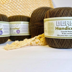 May include: Four spools of brown Bernat Handicrafter crochet thread. The label reads "Crochet Thread Fil de crochet Hilo para tejer a ganchillo" and features a purple number 5.