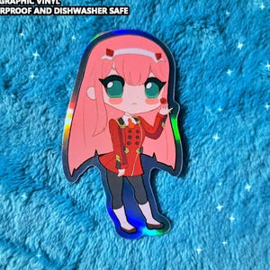 May include: Holographic vinyl sticker featuring a chibi anime character with pink hair and a red uniform. The sticker is approximately 2.5 to 3.5 inches in size and is waterproof and dishwasher safe.