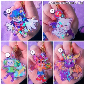 Puede incluir: Cinco llaveros holográficos iridiscentes con personajes de dibujos animados. Los llaveros miden aproximadamente 7,6 cm de alto. Los personajes incluyen un gato con alas, un murciélago blanco, un robot verde, un zorro rojo y un dragón morado.