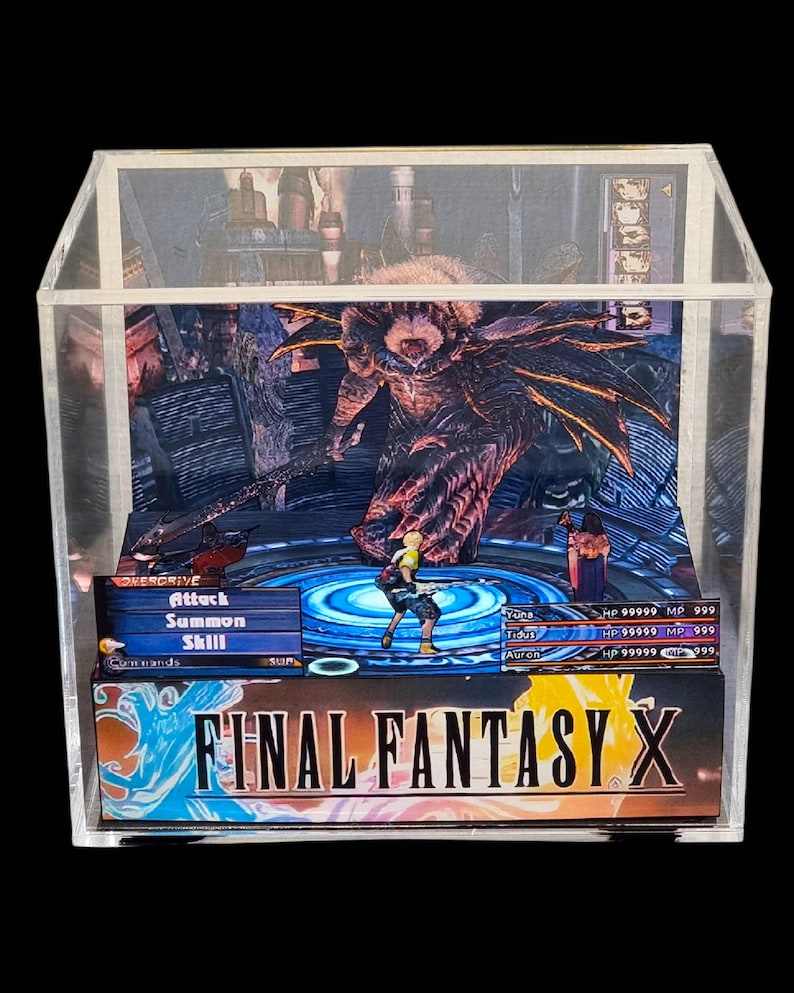 May include: A Final Fantasy X diorama in a clear acrylic display case. The scene depicts a battle with characters and a monster. The game's title is displayed at the bottom. The diorama is a collectible item.