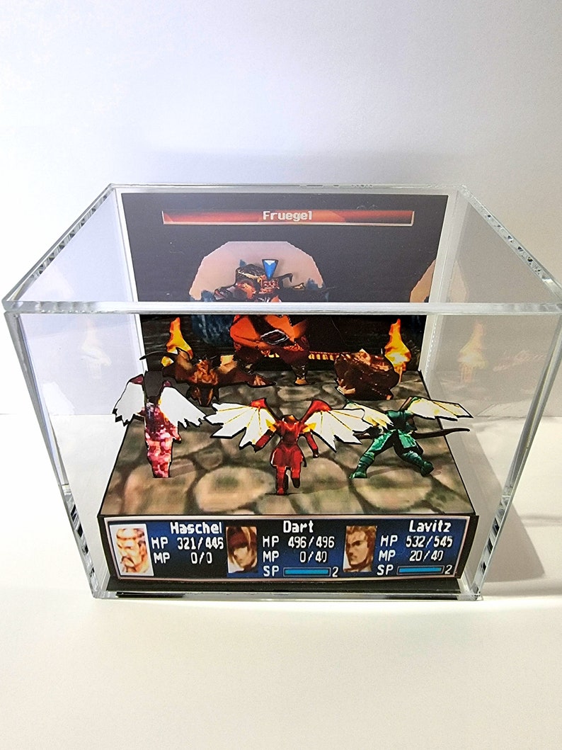 Pode incluir: Um diorama 3D de uma cena de batalha de um videogame com quatro personagens: Haschel, Dart, Lavitz e Fruegel. Os personagens est&atilde;o em p&eacute; em um terreno rochoso marrom com chamas ao fundo. O diorama est&aacute; fechado em uma caixa de acr&iacute;lico transparente.