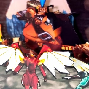 Pode incluir: Uma cena de papercraft com tema de fantasia com uma figura alada vermelha e branca, uma figura alada verde e uma figura grande, laranja e marrom no fundo.
