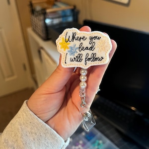 May include: White felt badge reel with the text "Where you lead I will follow" in black cursive. The badge reel has a pearl chain and a clear plastic clip.