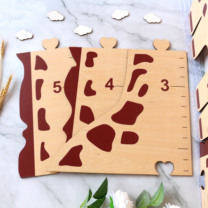 May include: Wooden giraffe growth chart with red spots and numbers 3, 4, and 5. The chart is made of light wood and has a brown stain.