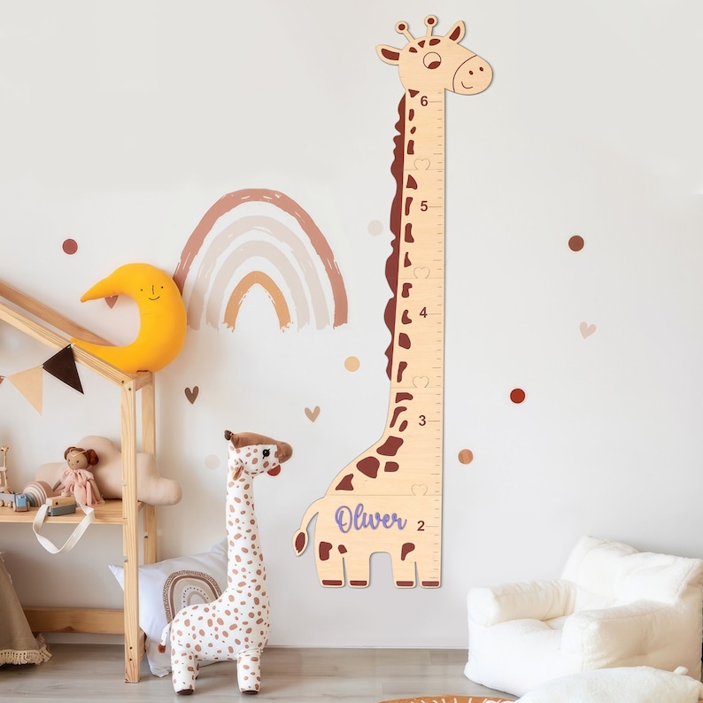 May include: A wooden giraffe growth chart with a brown and tan color scheme. The giraffe has a heart-shaped pattern on its neck and a purple name tag that says "Oliver". The chart is marked with numbers from 2 to 6.