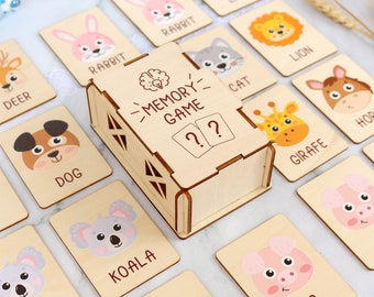 May include: Wooden memory game with a box that says "Memory Game" and question marks. The game features pairs of cards with different animal illustrations, including a deer, rabbit, lion, dog, koala, giraffe, pig, and horse.