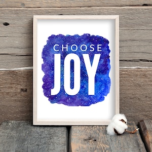 Puede incluir: Una impresi&oacute;n enmarcada con un fondo de galaxia acuarela y el texto "Choose Joy" en blanco.