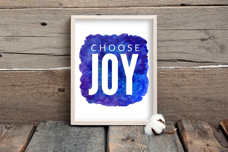 Puede incluir: Una impresi&oacute;n enmarcada con un fondo de galaxia acuarela y el texto "Choose Joy" en blanco.