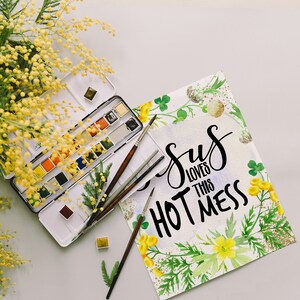 Puede incluir: Una pintura de acuarela con un dise&ntilde;o floral y el texto "Jesus loves this hot mess". La pintura est&aacute; rodeada de una paleta de acuarela, pinceles y una rama de mimosa amarilla.
