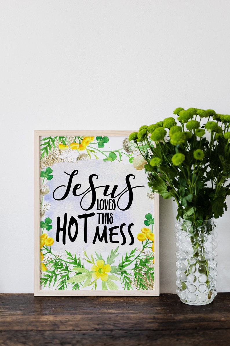 Puede incluir: Una impresi&oacute;n enmarcada con un fondo de acuarela de hojas verdes y flores amarillas. El texto "Jesus loves this hot mess" est&aacute; escrito en letras cursivas negras.