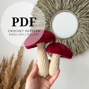Può includere: Un documento PDF con schema per uncinetto raffigurante due funghi di peluche fatti a mano con cappelli in velluto rosso scuro e gambi color crema. Il testo sull'immagine recita PDF CROCHET PATTERN ENGLISH / POLSKI, indicando le lingue disponibili.