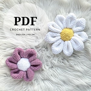 May include: PDF crochet pattern for a white daisy and a purple daisy with a white center. The pattern is available in English and Polish.