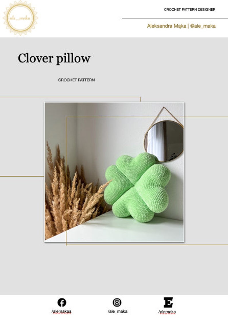 May include: A green crocheted clover-shaped pillow on a white surface. The pillow is in focus, and the background is blurred.