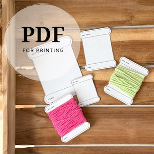 May include: A collection of white printable yarn label templates with the text "PDF FOR PRINTING". Two spools of yarn are visible, one bright pink and one light green. The labels include spaces for "yarn name" and "color".