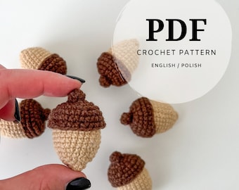 Puede incluir: Varias bellotas pequeñas tejidas a ganchillo con cuerpos de color beige y sombreros de color marrón oscuro. Una superposición circular contiene el texto PDF CROCHET PATTERN ENGLISH / POLISH. Los objetos tienen puntadas visibles.