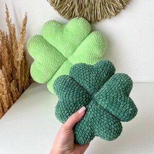 May include: Two plush clover-shaped pillows. One is green and the other is a darker green.