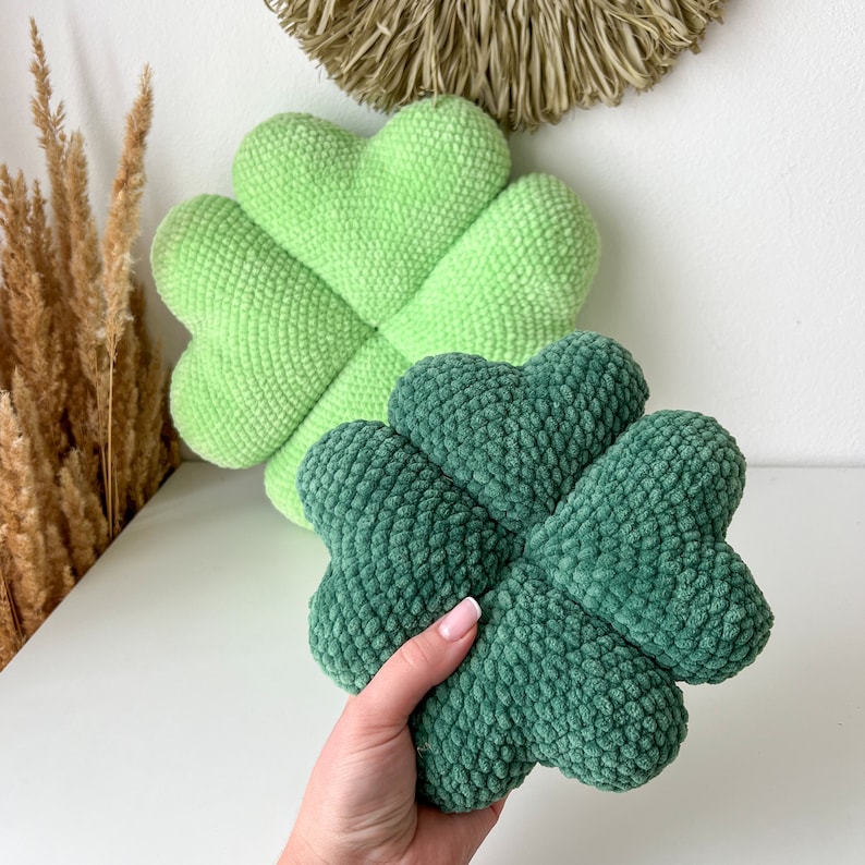 May include: Two plush clover-shaped pillows. One is green and the other is a darker green.