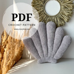 May include: A grey, seashell-shaped crochet cushion. The cushion has a textured surface and is made of a soft, plush material. The image also includes text that says "PDF CROCHET PATTERN ENGLISH/POLSKI".