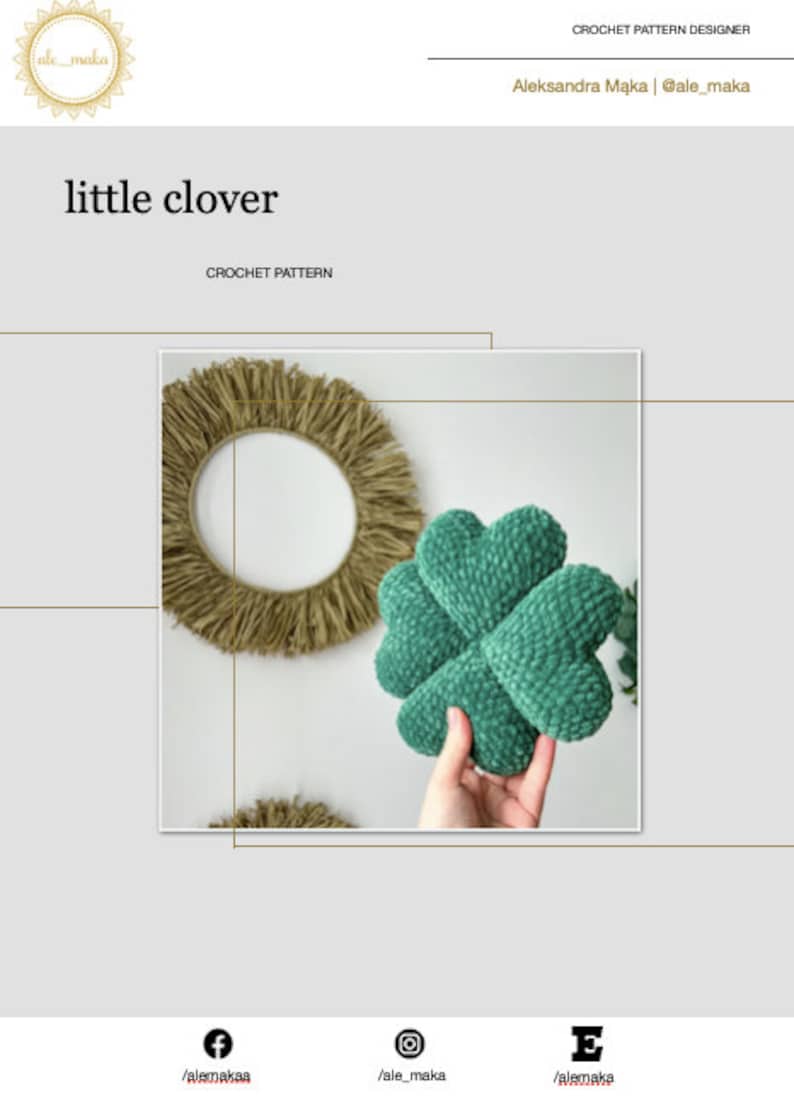 May include: A green crocheted clover-shaped pillow with a textured surface. The pillow is being held in a hand.