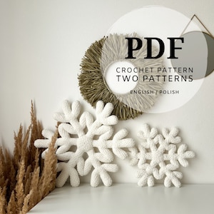 May include: Two white crocheted snowflakes, one larger than the other, against a white wall. The text "PDF CROCHET PATTERN TWO PATTERNS ENGLISH/POLISH" is visible in the image.