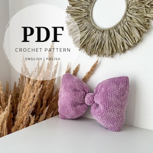 Puede incluir: Un documento PDF de patrón de ganchillo en inglés y polaco que presenta un cojín texturizado en forma de lazo de color morado claro. El texto en la imagen dice PDF CROCHET PATTERN ENGLISH / POLISH, indicando los idiomas de las instrucciones.