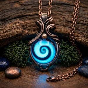 May include: A pendant necklace featuring a round, glowing blue glass orb with a central spiral design. The orb is encased in intricate, dark copper wire wrapping that forms a decorative bail at the top, suspended from a matching copper chain.