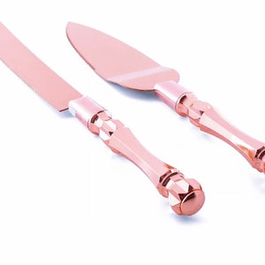 Puede incluir: Un juego de dos cuchillos para cortar pasteles de color oro rosa con mangos adornados. Los cuchillos están diseñados para cortar pasteles de boda.