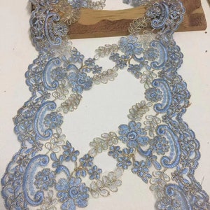 May include: Blue and gold lace trim with a delicate floral pattern. The lace is soft and sheer, with a subtle shimmer.