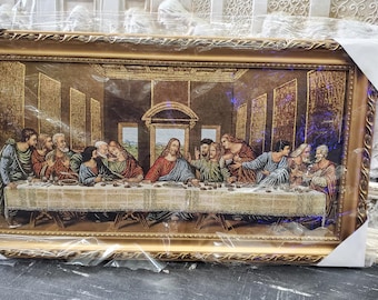 May include: A framed tapestry depicting The Last Supper, a famous Renaissance painting by Leonardo da Vinci. The tapestry features 13 figures seated around a table, with Jesus Christ at the center.