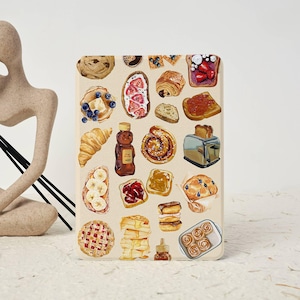 May include: A colorful illustration of various breakfast pastries, including croissants, cinnamon rolls, and toast, on a beige background.