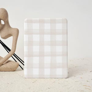 May include: A rectangular cover featuring a beige and white gingham pattern. The cover has rounded corners and a soft, textured appearance. The background is a neutral, off-white colour.