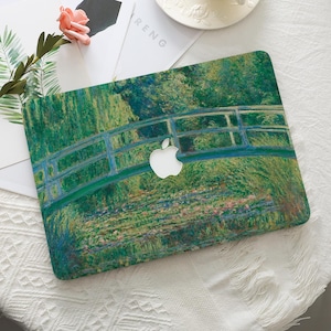 Puede incluir: Una funda para portátil con una pintura impresionista de un puente sobre el agua, en tonos verdes y azules. El logotipo de Apple es visible. La palabra "RENG" está impresa en una superficie blanca.